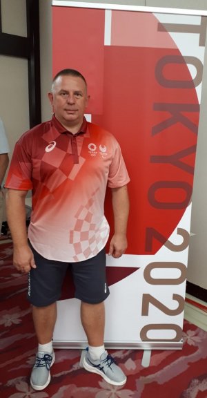 Aspirant sztabowy Sławomir Milczarek stoi przed logo igrzysk.