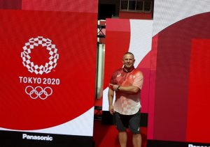 Aspirant sztabowy Sławomir Milczarek stoi przed logo igrzysk.