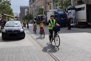 Ulica Piotrkowska, kolumna rowerzystów porusza się gęsiego jeden za drugim po jezdni.