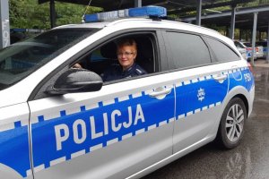 Policjantka siedzi w oznakowanym radiowozie.