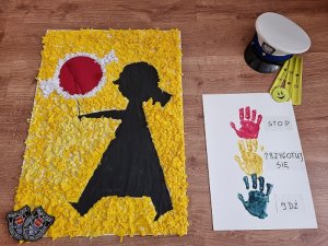 pPrace dzieci: znak drogowy dziewczynka z lizakiem oraz sygnalizator z kolorowych odcisków dłoni, powyżej czapka policjanta ruchu drogowego, na dole plakietki komendy miejskiej policji w Łodzi
