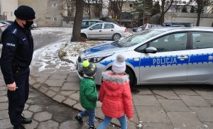 Policjant z dziećmi idący do radiowozu policyjnego