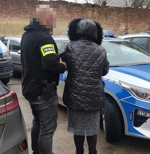 Zatrzymana kobieta podejrzana o kradzież pieniędzy pokrzywdzonej prowadzona przez policjanta.