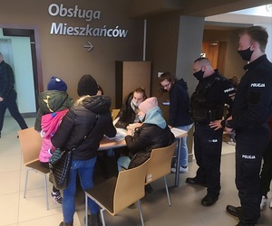 Policjanci przy stoisku wypełniania wniosków o nadanie numeru pesel dla uchodźców.