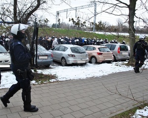 Policjanci eskortują kibiców gości na teren stadionu.