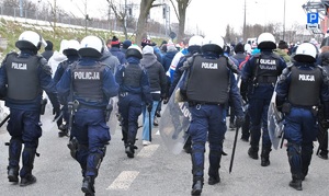 Policjanci eskortują kibiców gości na stadion.