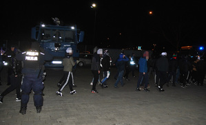 Kibice gości opuszczają stadion w otoczeniu policjantów.