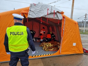 Policjant stoi przed namiotem medycznym