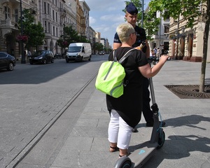 Policjanci rozmawiają z kobietą, która jechała hulajnogą po ulicy Piotrkowskiej w Łodzi.