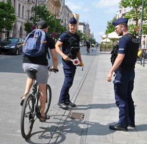 Policjanci zatrzymujący do kontroli mężczyznę jadącego rowerem.