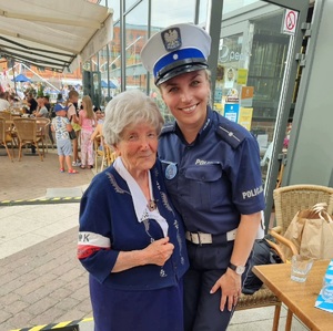 Policjantka stoi ze starszą kobietą.