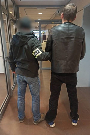 Policjant prowadzi korytarzem komisariatu podejrzanego.
