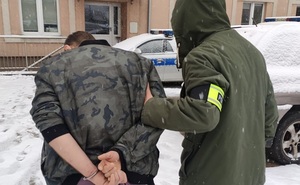 Policjant prowadzi zatrzymanego na terenie Komendy Miejskiej Policji w Łodzi