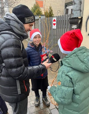Dzieci w rozmowie z dziennikarzem, który trzyma w dłoni mikrofon.