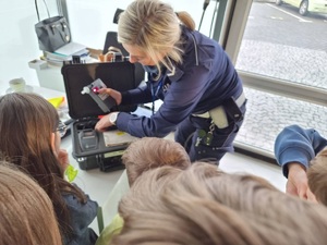 Policjantka prezentuje dzieciom sprzęt wykorzystywany w służbie.