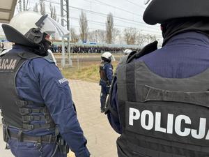 Umundurowani policjanci obserwują wysiadających z pociągu kibiców.