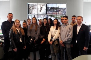 Komendant Miejski Policji w Łodzi inspektor Dariusz Dziurka wraz ze studentami stoi na tle ekranów w pomieszczeniu stanowiska dowodzenia.