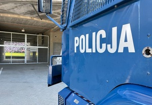 Napis policja na tle wejścia na stadion ŁKS Łódź.