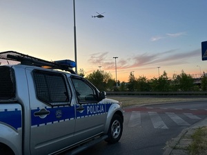 Radiowóz policyjny i widoczny na niebie helikopter policyjny.