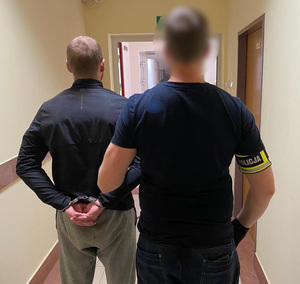 Nieumundurowany policjant prowadzi zatrzymanego sprawcę rozboju.