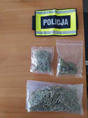 Woreczki foliowe z marihuaną zabezpieczone przez policjantów nad nimi opaska z napisem policja.