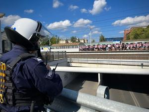 Policjant a w tle kibice Cracovii wysiadają z pociągu na dworcu Łódź Niciarniana.