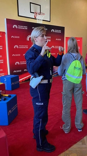 Policjantka tłumaczy słuchaczom zasady bezpieczeństwa w ruchu drogowym.