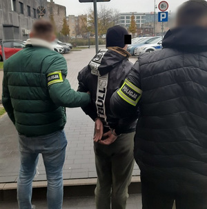 Policjanci prowadzą zatrzymanego.