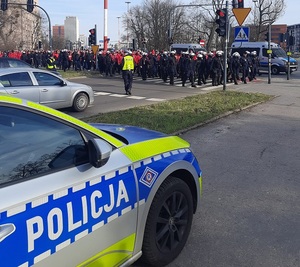 Policjanci Ruchu Drogowego Komendy Miejskiej Policji w Łodzi zabezpieczają skrzyżowanie w trakcie przemarszu kibiców.