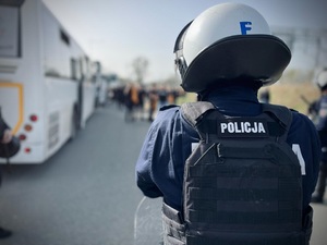 Funkcjonariusz obserwuje wysiadających z autokaru kibiców Korony Kielce.