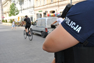 Napis policja na koszulce funkcjonariusza a w tle rowerzysta.