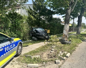 Radiowóz policyjny na miejscu zdarzenia, w tle rozbite auto.