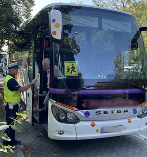 Policjant Ruchu Drogowego kontroluje trzeźwość kierowcy autobusu.