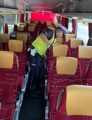 Policjant drogówki kontroluje stan techniczny autobusu.