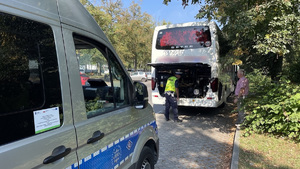 Policjant z drogówki kontroluje stan techniczny autobusu.