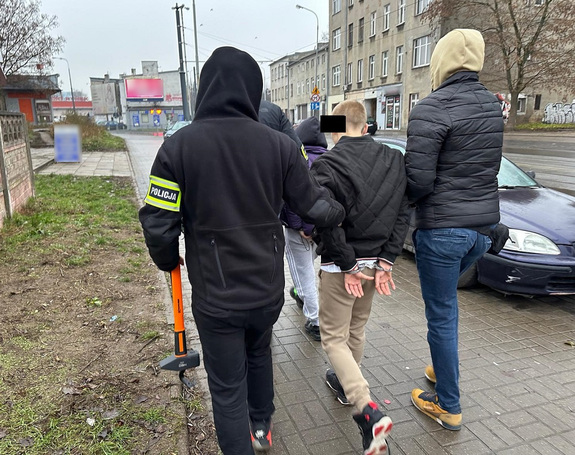 Policjanci prowadzą zatrzymanego mężczyznę i kobietę.