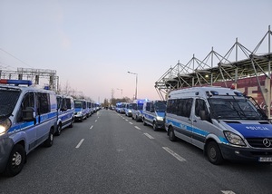 Oznakowane radiowozy policyjne przed stadionem.