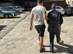 Policjant prowadzi zatrzymanego mężczyznę.