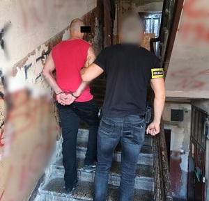 Policjant trzymają zatrzymanego mężczyznę.