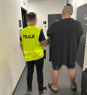 Policjant prowadzi zatrzymanego.
