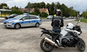 Policjant Wydziału Ruchu Drogowego Komendy Miejskiej Policji w Łodzi kontroluje motocyklistę.