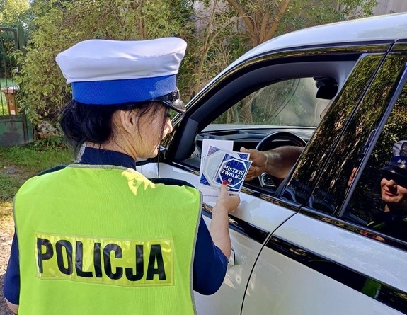 Policjantka wręcza materiały partnera akcji &quot;Zwolnij, mistrzu&quot;.