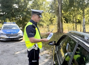 Policjant wręcza materiały partnera akcji &quot;Zwolnij, mistrzu&quot;.