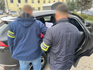 Policjanci pomagają wsiąść mężczyźnie do radiowozu.