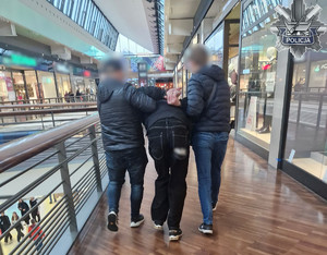 Policjanci prowadzą zatrzymanego mężczyznę.