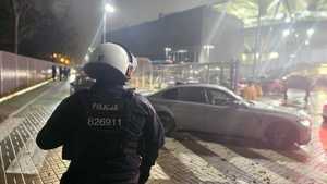 Policjant Oddziału Prewencji Policji w Łodzi na tle wjeżdżających na stadion pojazdów.