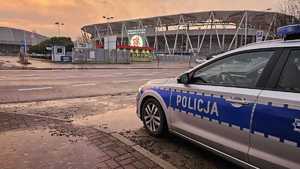 Policyjny radiowóz na tle stadionu.