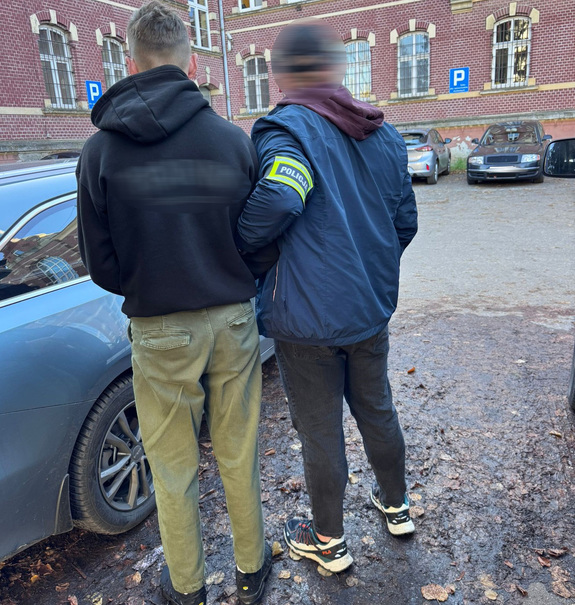 Zatrzymany prowadzony przez policjanta.