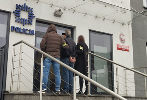 Policjanci wprowadzają zatrzymanego mężczyznę do komisariatu.