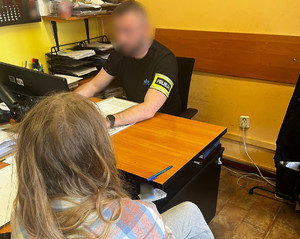 Policjant prowadzi czynności z zatrzymaną kobietą.